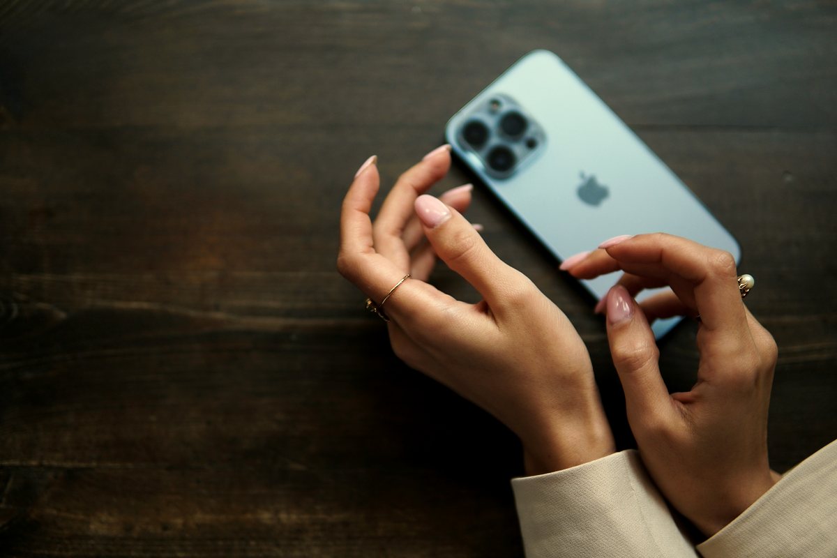 Hands holding a phone face-down on a wooden table