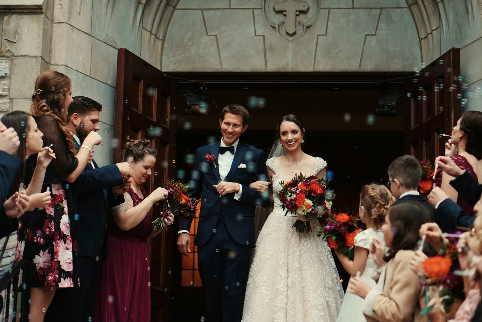 A newlywed couple leaving their ceremony surrounded by celebrating guests