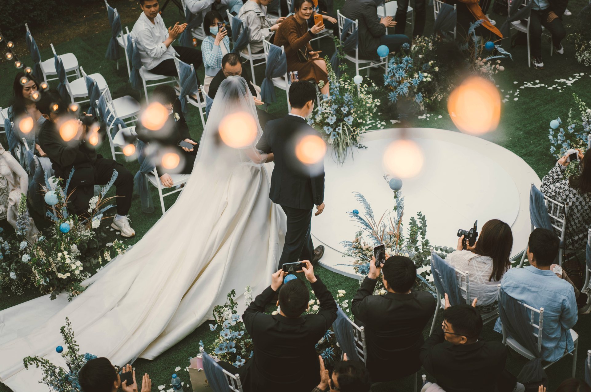 Guests watching a couple walk down the aisle through their raised phone screens